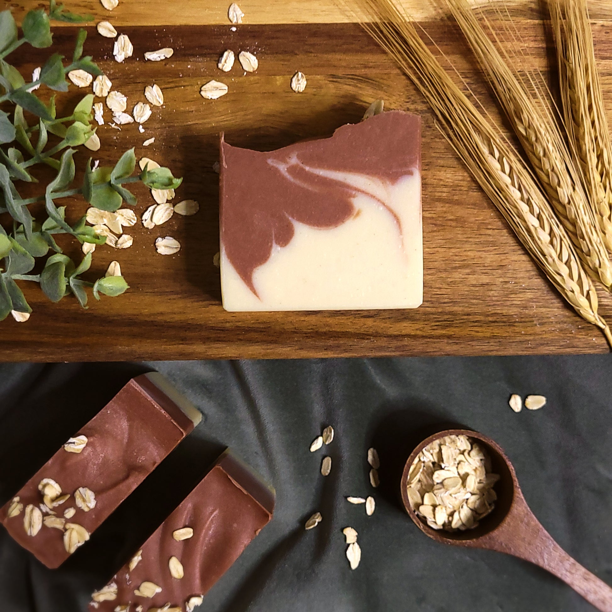 Natural soap bar colored with clays and oats on a wooden board and a dark fabric.