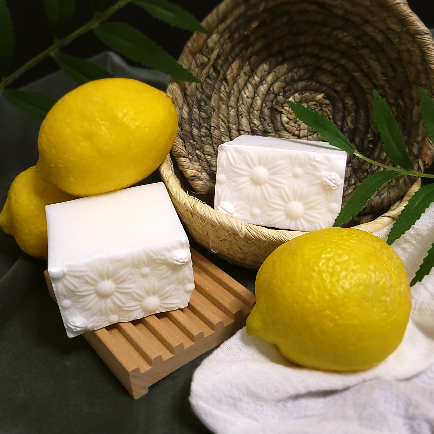 Dish soap bars on a wooden soap dish and woven basket with lemons around.
